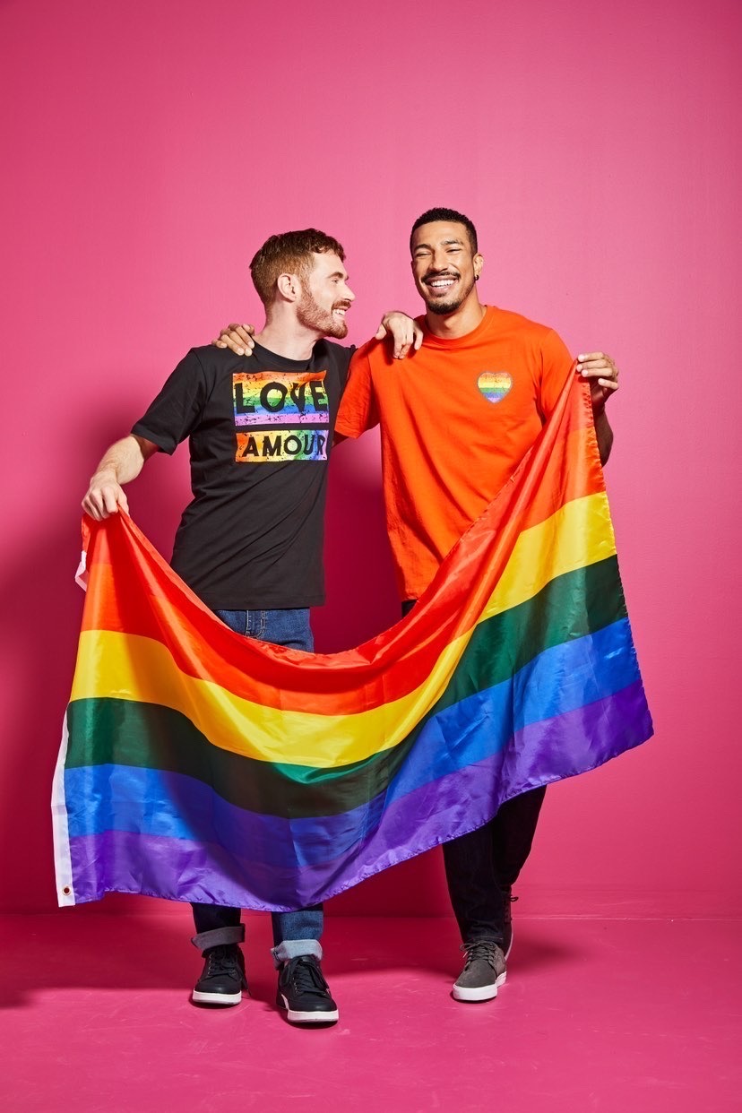 two men holding a rainbow flag