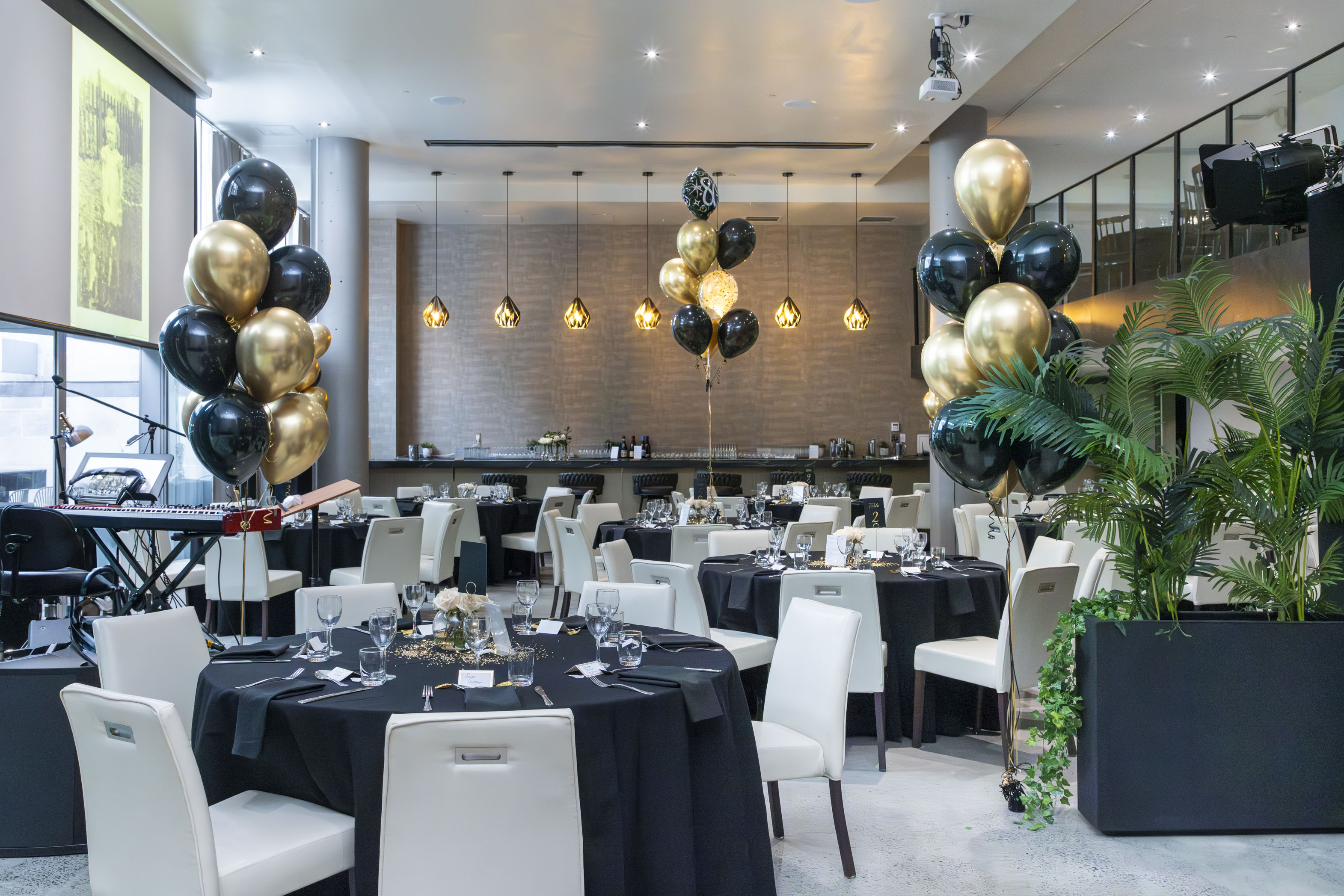 a room with tables and black and gold balloons